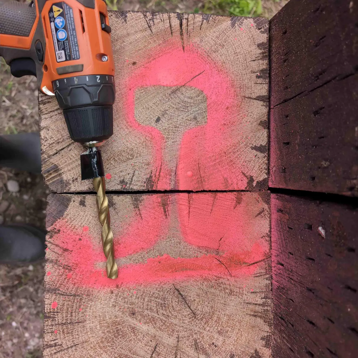 A Ridgid 12v drill with a large drill bit in it. There is tape fastened around the bit serving as a depth gauge.