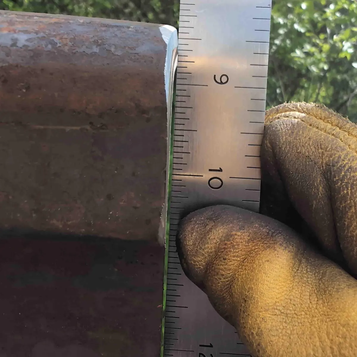 A close up showing the face of the rail anvil with a straight edge against it. You can see light thru the gap.